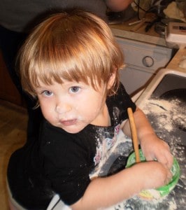 a little girl covered in flour with a bowl
