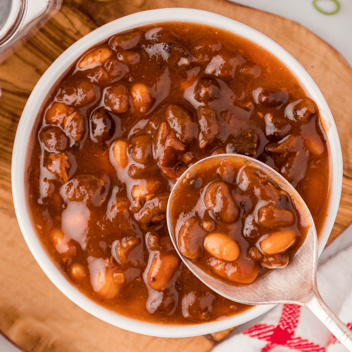 BBQ baked beans with bacon in a white bowl with a spoon