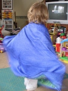A little girl wearing a superhero cape