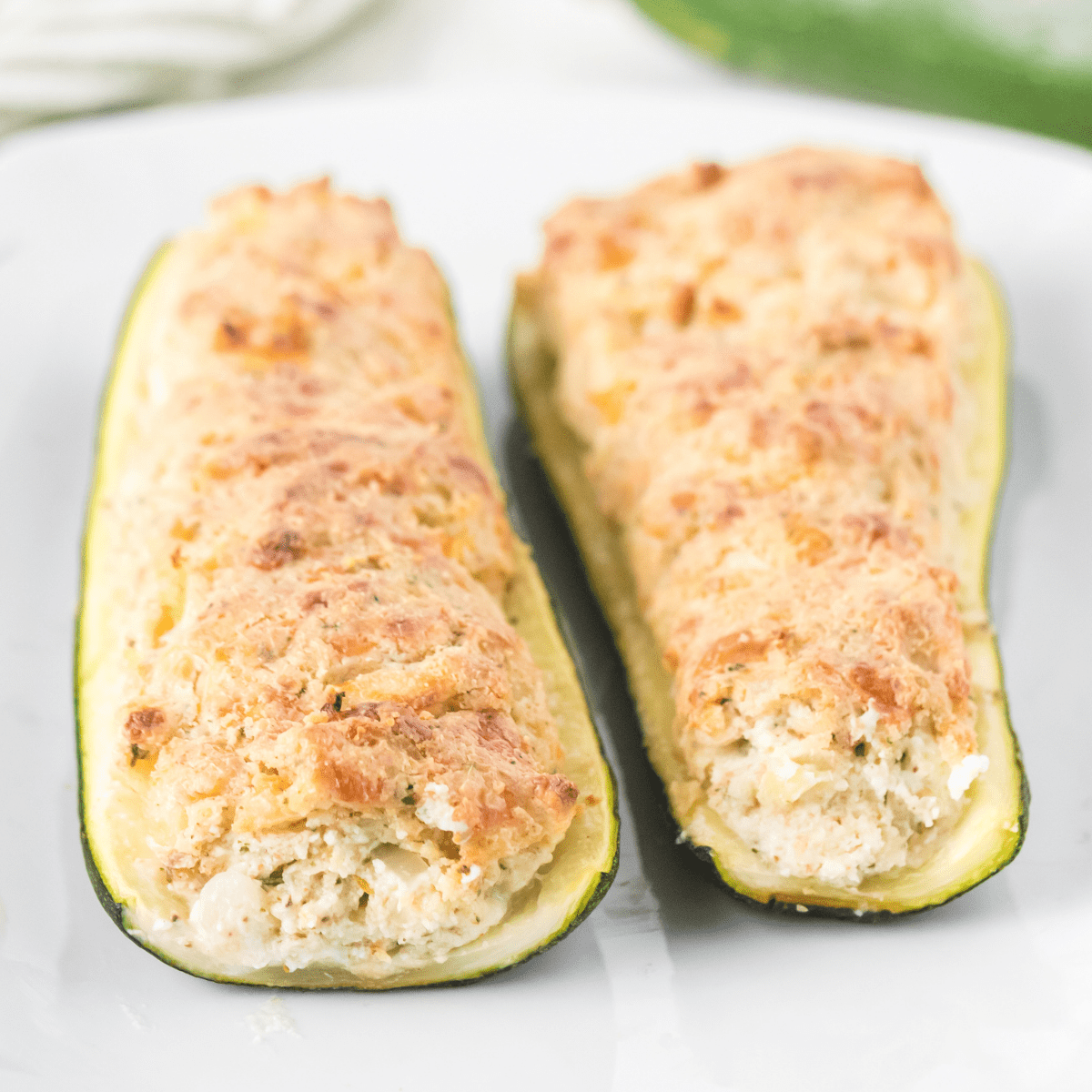 cheese stuffed zucchini boats on a white plate