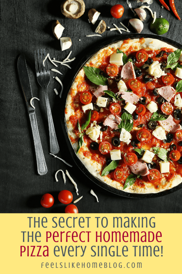 a knife and fork with a pizza with ham, cheese, spinach, and tomatoes