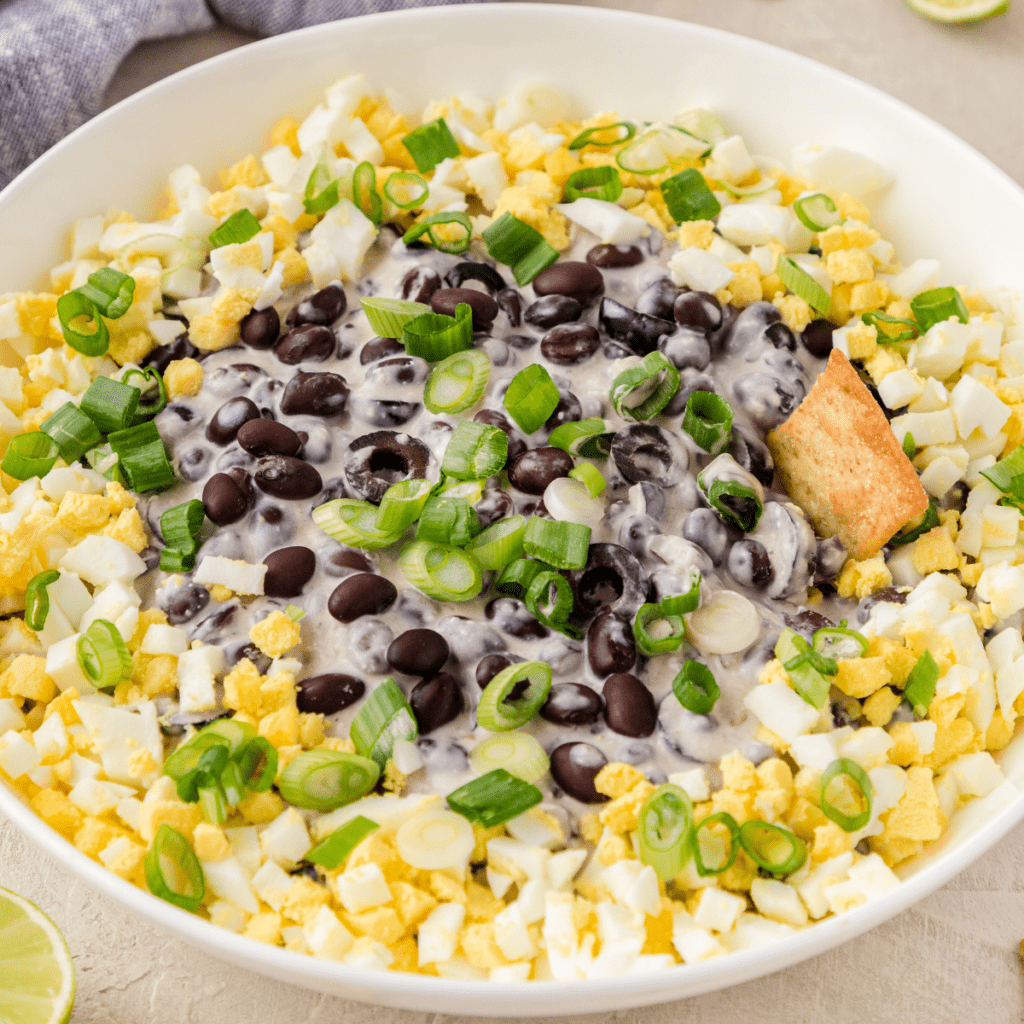 a white bowl filled with cowboy caviar or cream cheese bean dip with hard boiled eggs