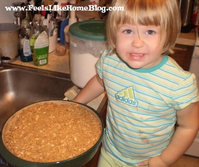 A little girl standing in front of a bowl of apple crisp