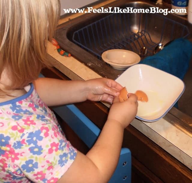 a little girl with a broken eggshell in a bowl