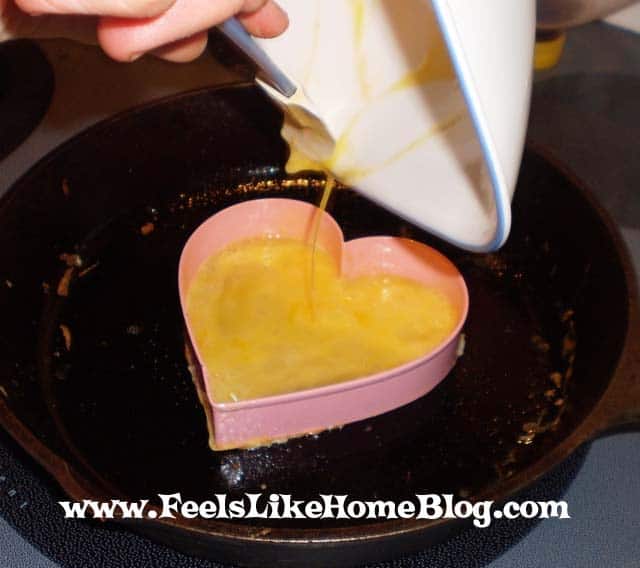 Egg being poured into a heart cookie cutter