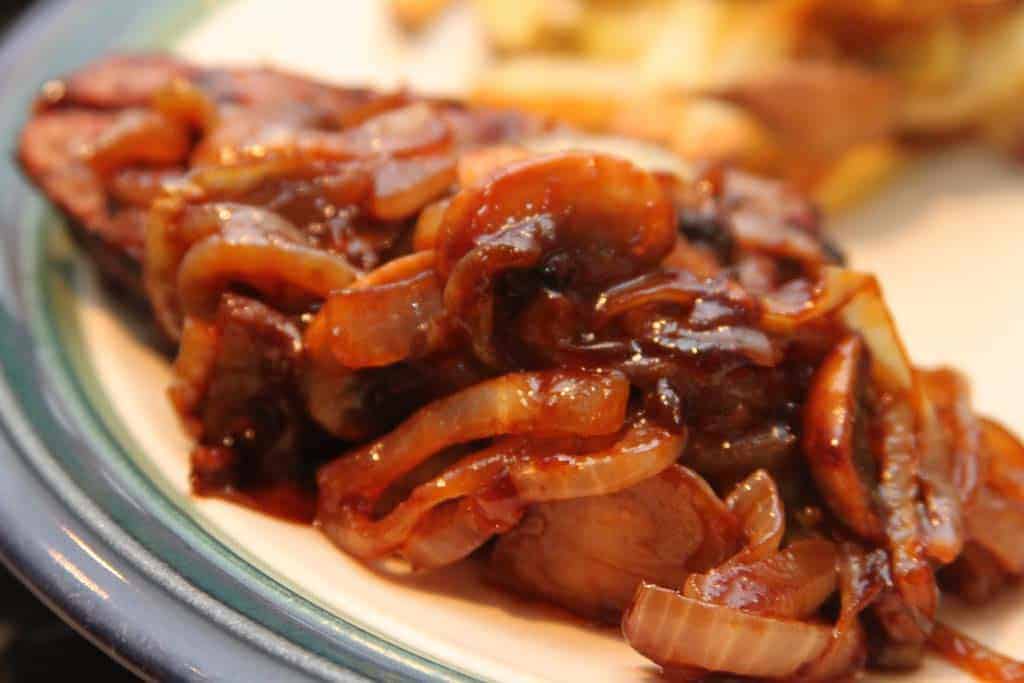 A close up of a plate of food, with Steak and Onion and Mushroom