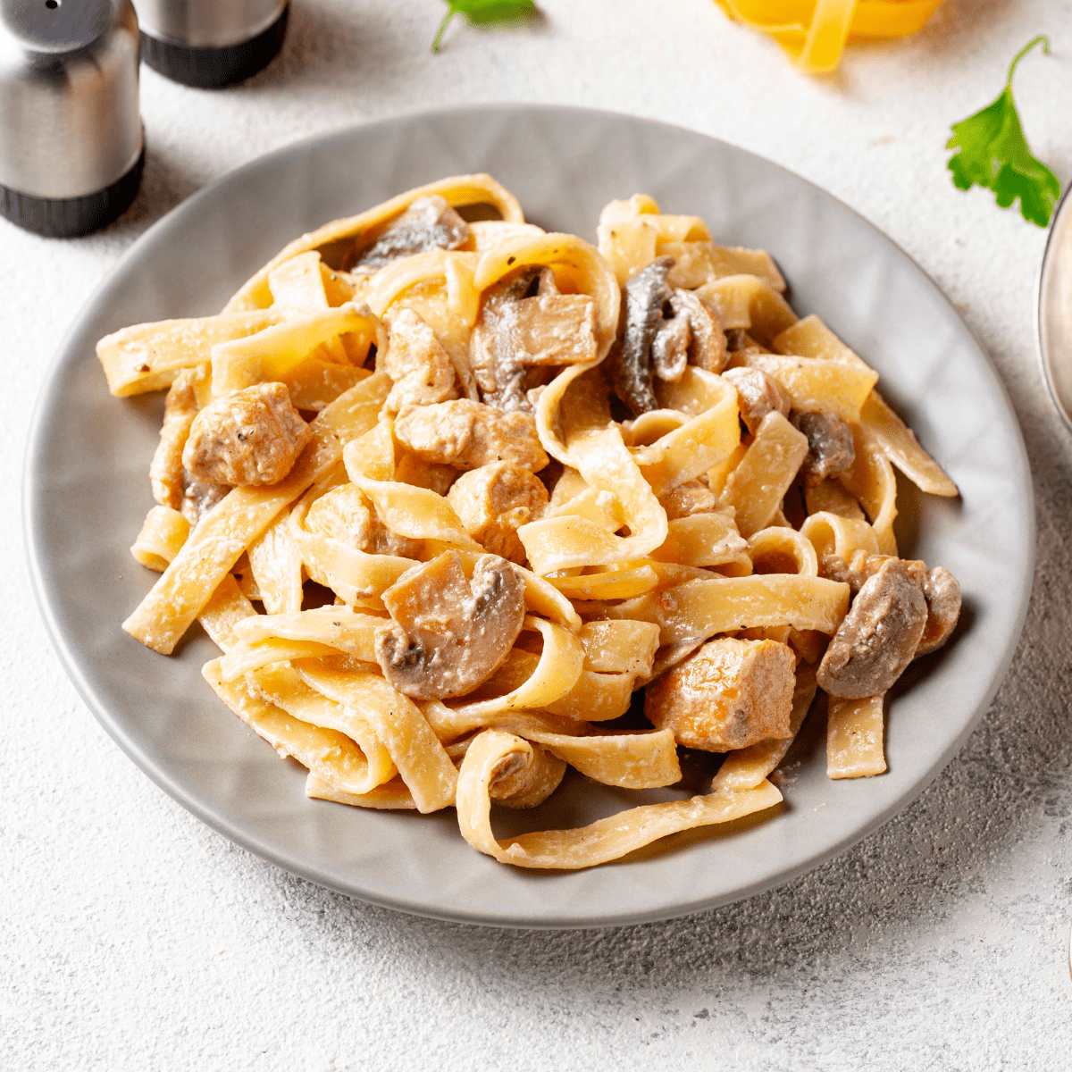 a plate of noodles topped with chicken and mushrooms