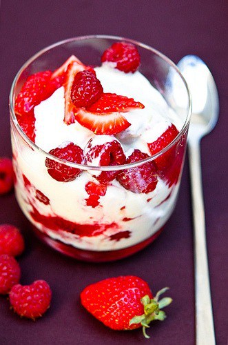 a strawberry and raspberry trifle in a glass with a spoon