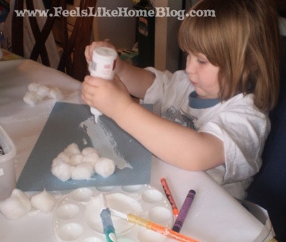 a little girl squeezing glue on a piece of blue paper