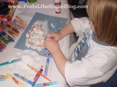 a little girl decorating a cloud made of cotton balls