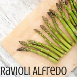 asparagus on a wooden cutting board with the title "ravioli alfredo with asparagus and mushrooms"
