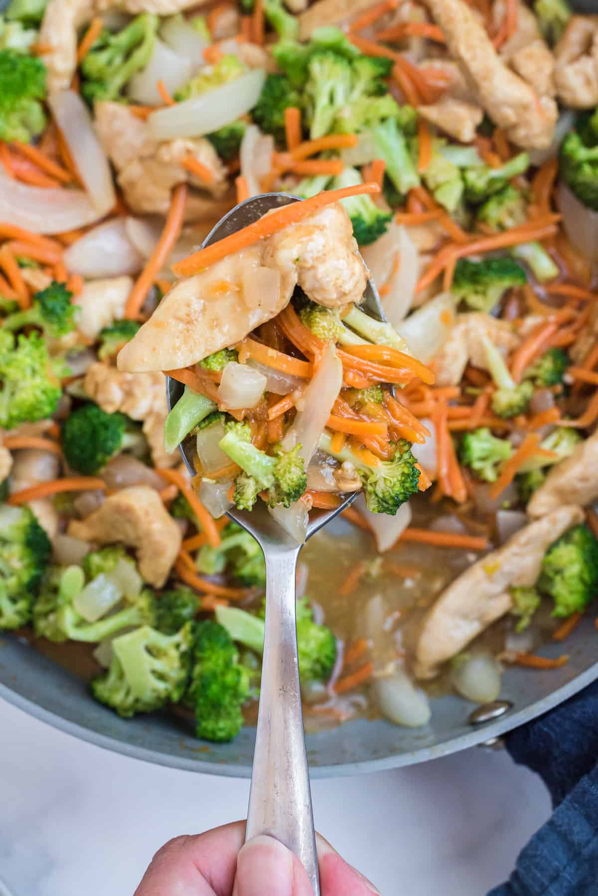 a spoonful of garlic chicken stir fry held over the wok