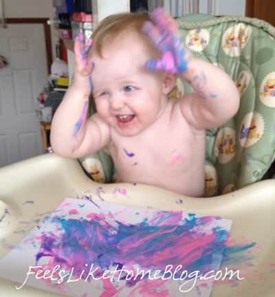 A baby smearing paint in her hair
