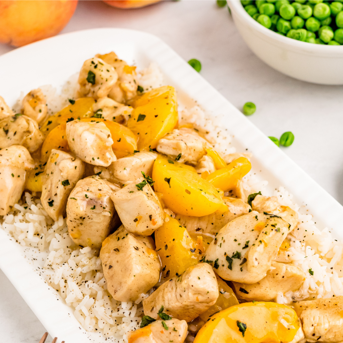 chicken and peaches stir fry on a white platter