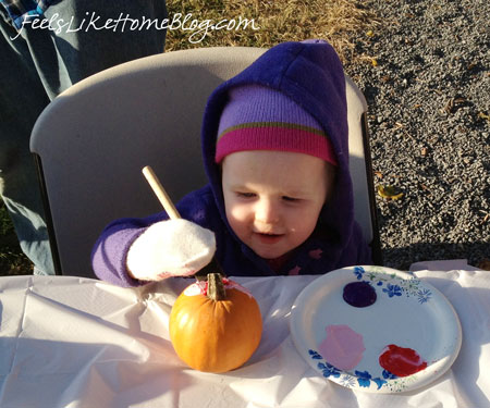 A little sister painting a pumpkin