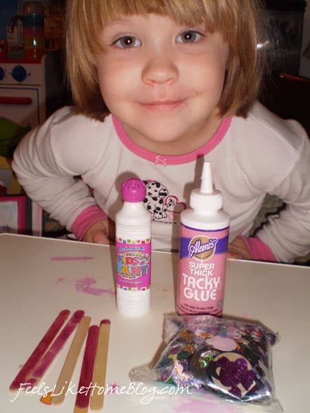 A little girl sitting at a table with craft supplies