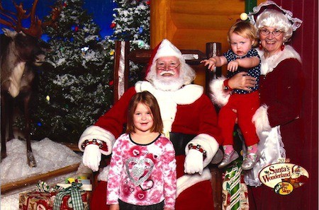 A little girl posing for a picture with Santa