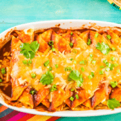 half of a platter full of healthy chicken enchiladas topped with cheese, cilantro, and green onions