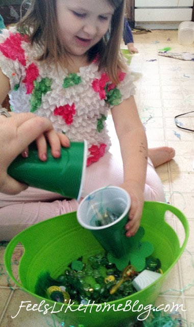 A little girl pouring objects into a cup