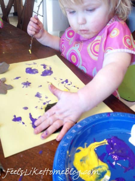 A little girl sitting at a table with a plate of paint