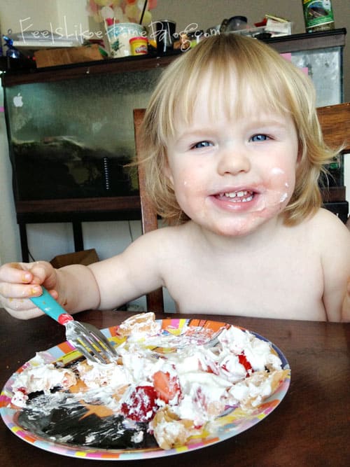 A little girl sitting at a table eating food, with Strawberry and Waffle