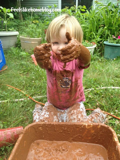 A little girl dropping mud into a bucket