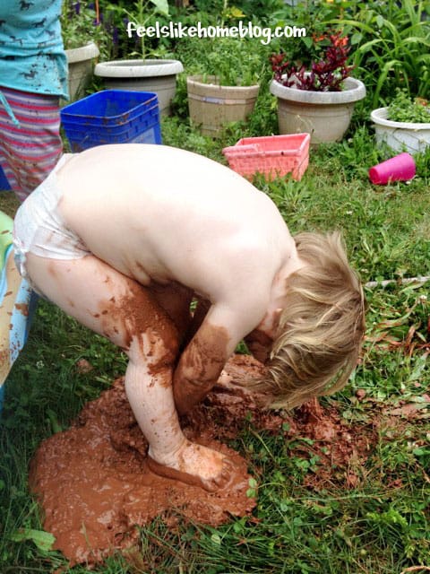 The little girl is now wearing only a diaper and is still covered in mud