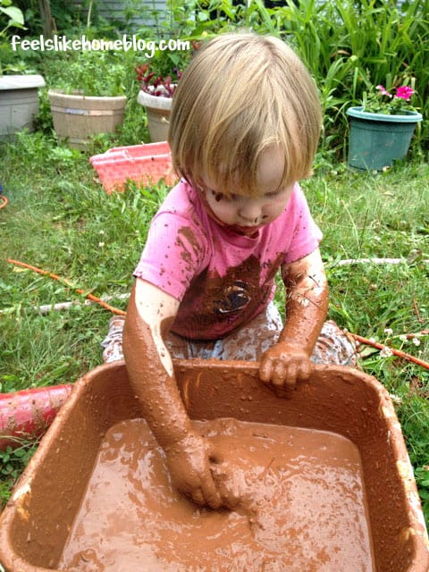 A small child playing in a pan of mud