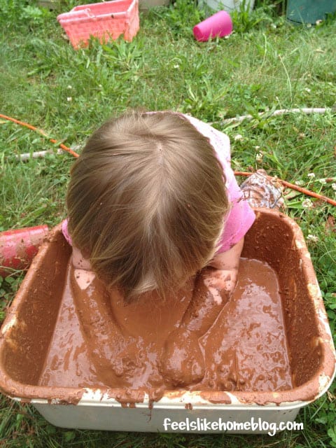 A little girl up to her armpits in mud