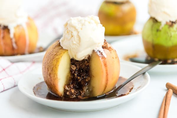 a baked apple with filling running out and a scoop of ice cream on top