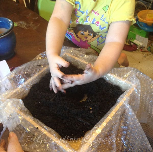 A little girl putting soil into her fairy garden