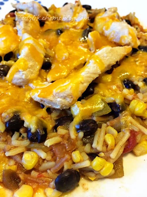 a close up of chicken with rice and beans topped with cheese