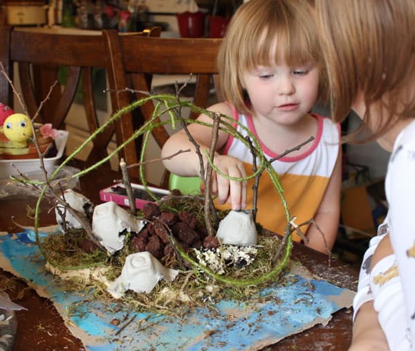 A small child adding rocks to her island