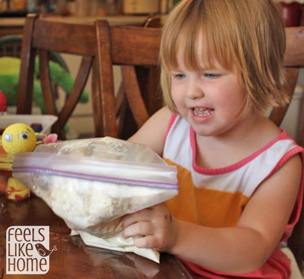 A little girl mixing something in a bag