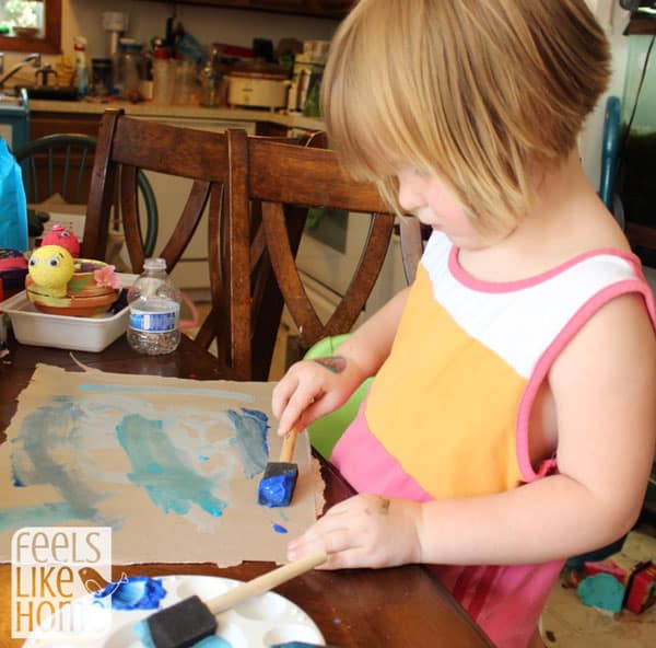 A little girl painting cardboard