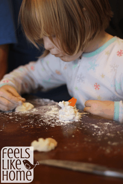 A little kid that is making a marzipan snowman