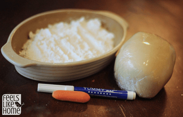 A bowl of powdered sugar, marzipan, carrots, and a food marker