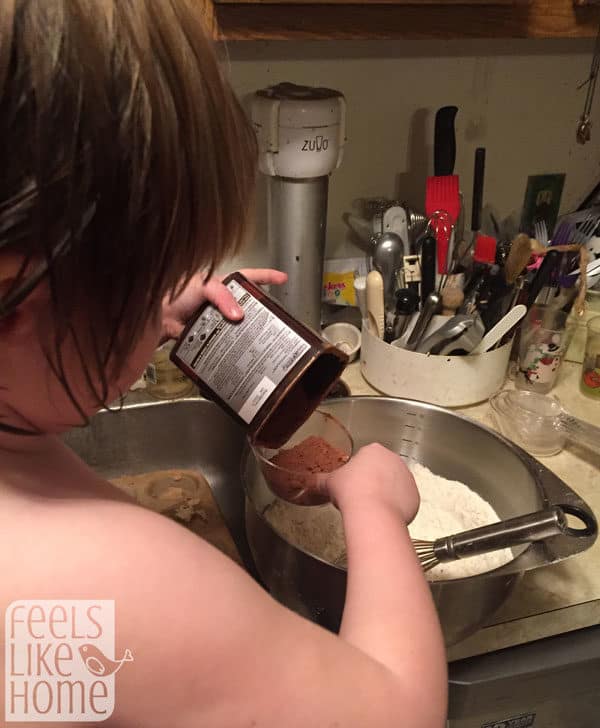 young girl measuring cocoa powder into a mixing bowl