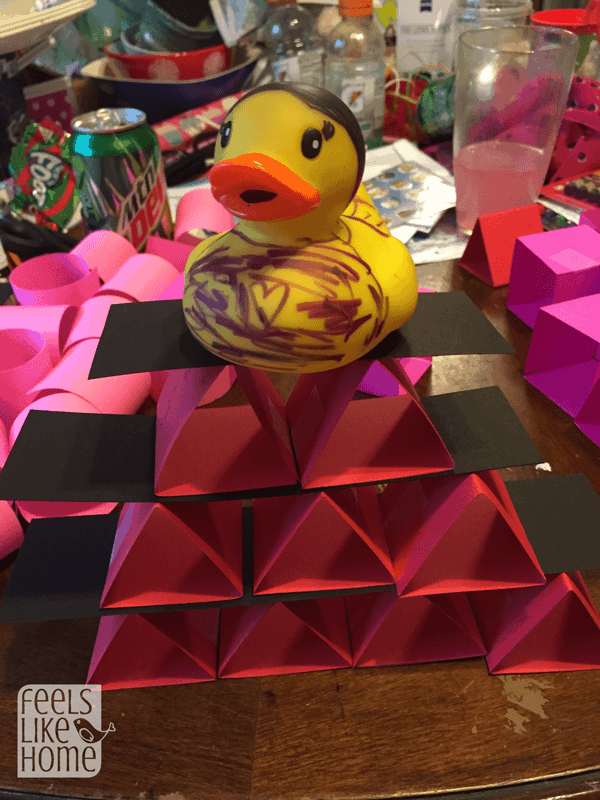 a bunch of paper triangles in a pyramid with a rubber duck on top