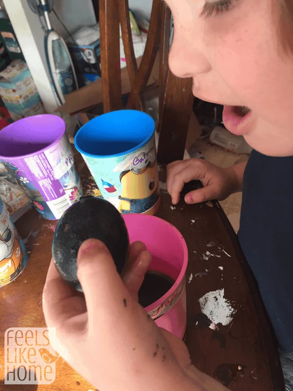 a little girl holding a black egg