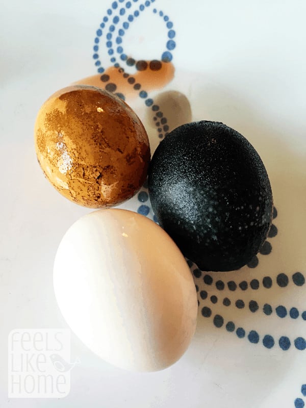 three eggs, one is brown, one is black, and one is white