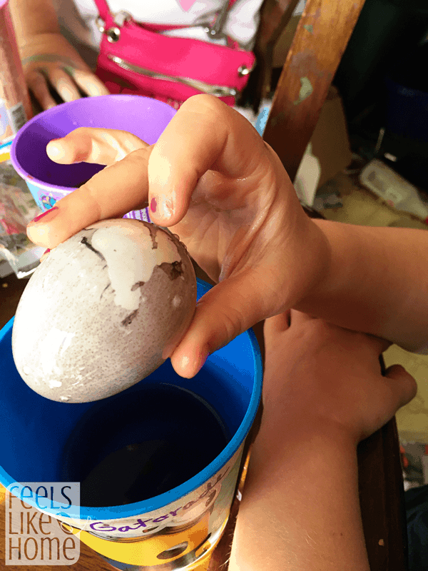 a hand holding a gray egg with some of the gray film wiped off