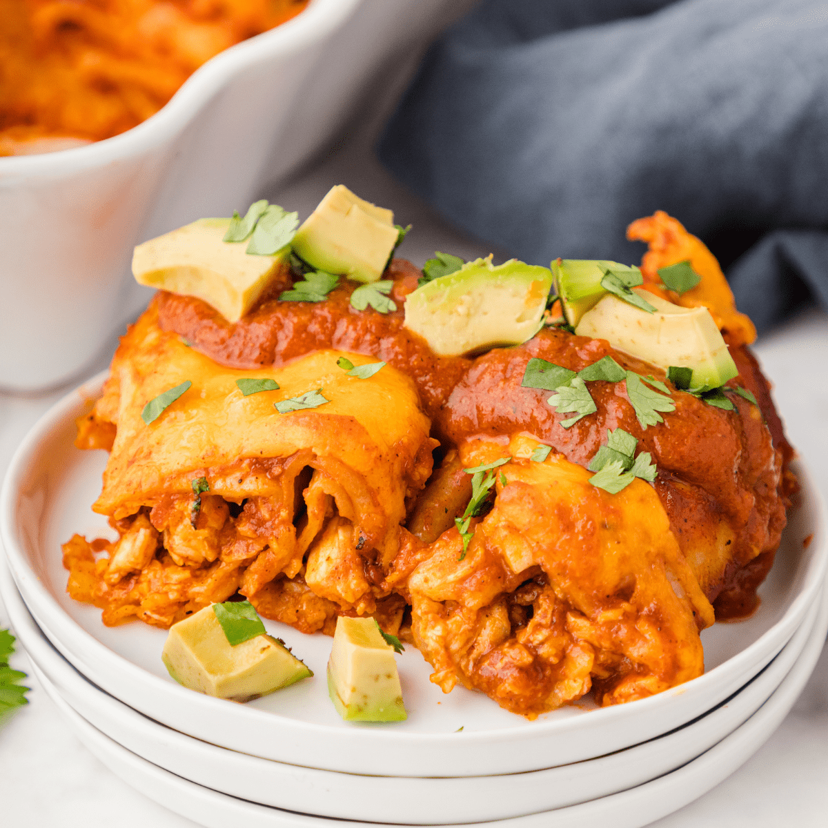 a BBQ chicken enchilada cut in half and topped with enchilada sauce and chopped avocado