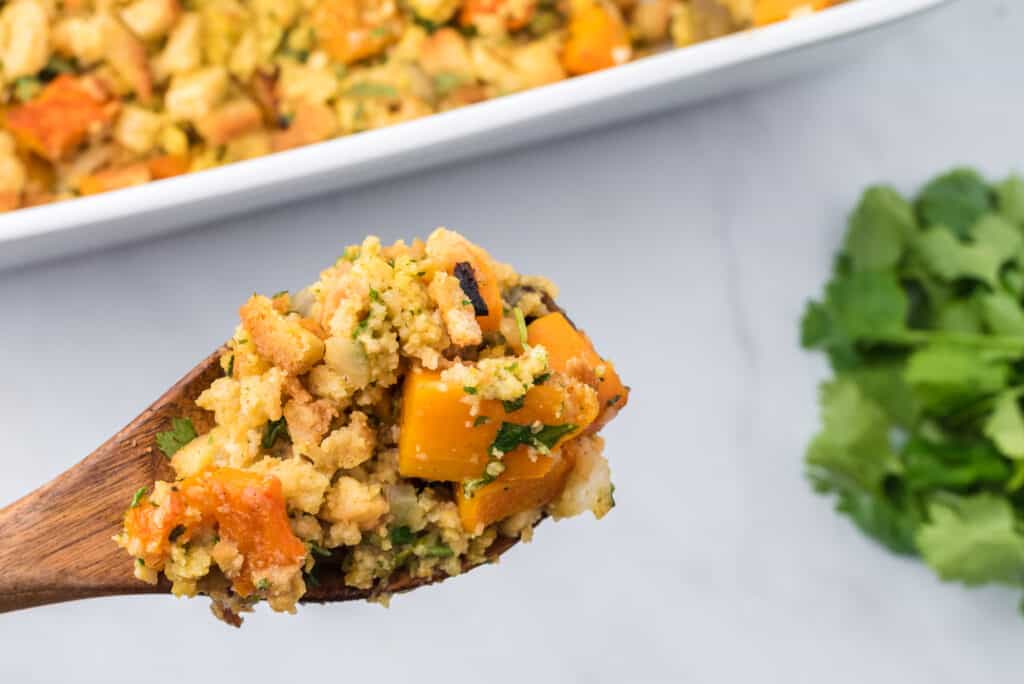 cornbread stuffing with roasted vegetables on a wooden spoon