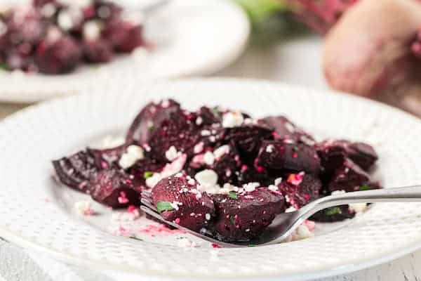 roasted red beets with feta cheese on a white plate with a fork