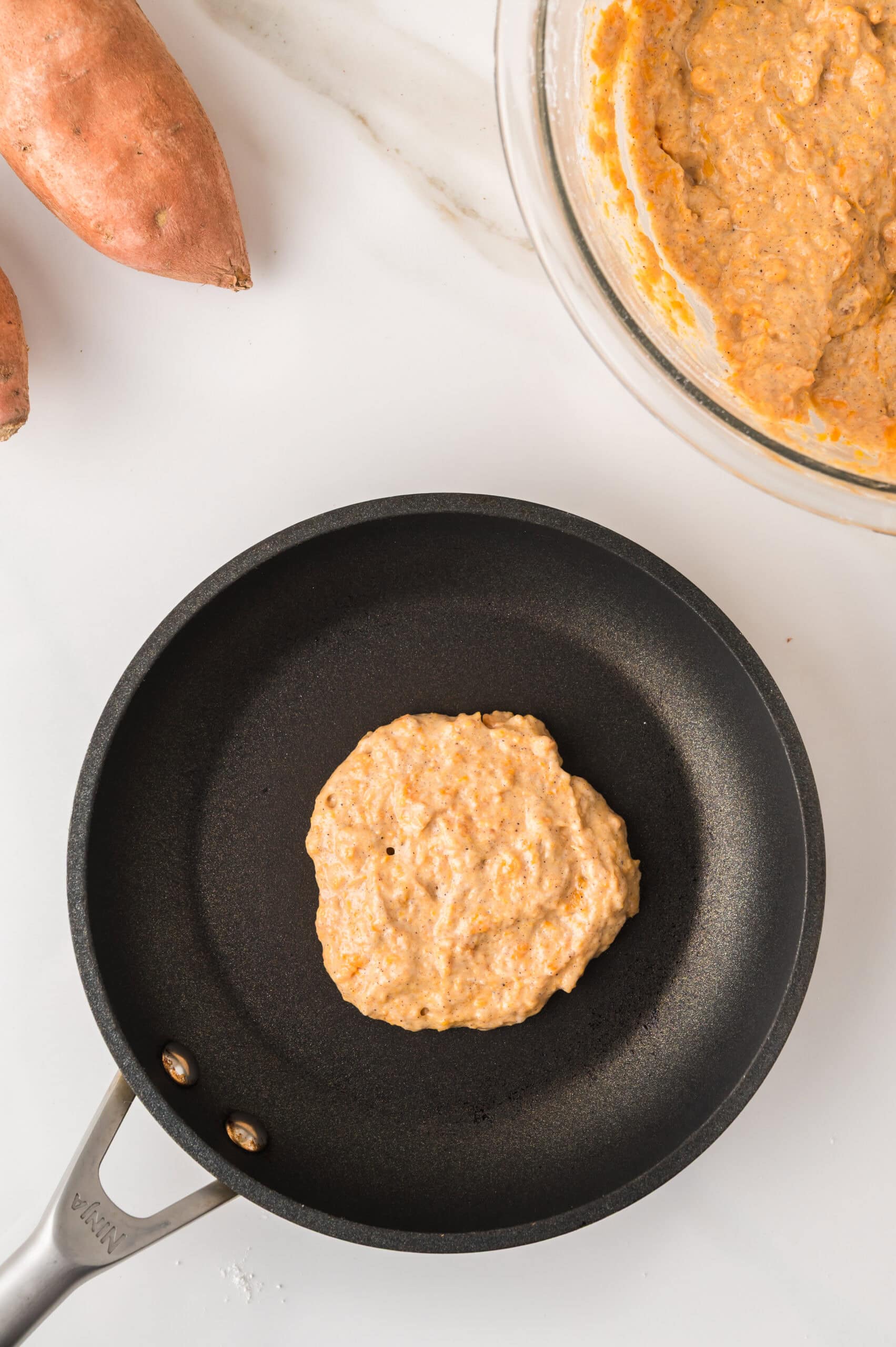 Sweet potato pancakes cooking in skillet
