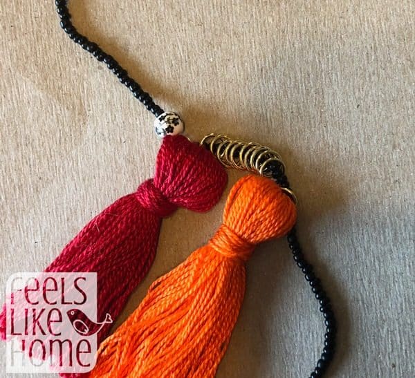 Attach the jump rings to the beaded cord with more jump rings in between the tassels
