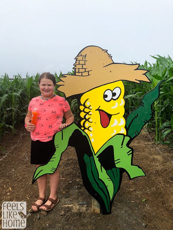 A girl standing in front of a corn cob