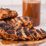grilled marinated chicken sliced on a wooden cutting board