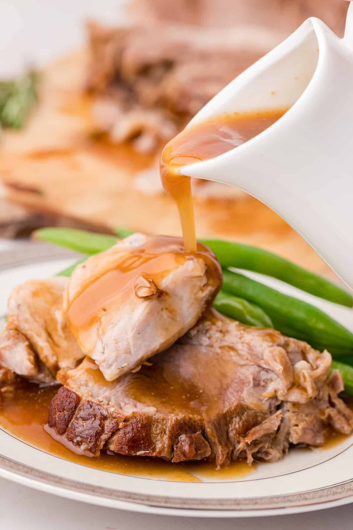 sweet balsamic gravy being poured over Instant Pot pork roast on a plate